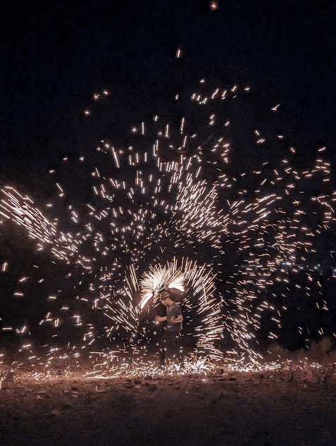 Man carrying out a fire perfomance with sparklers in the dark